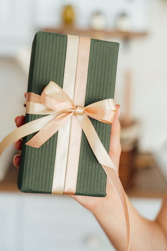 pexels photo 5486845 A chic green gift box wrapped with satin ribbon held by a hand, ideal for any celebration.